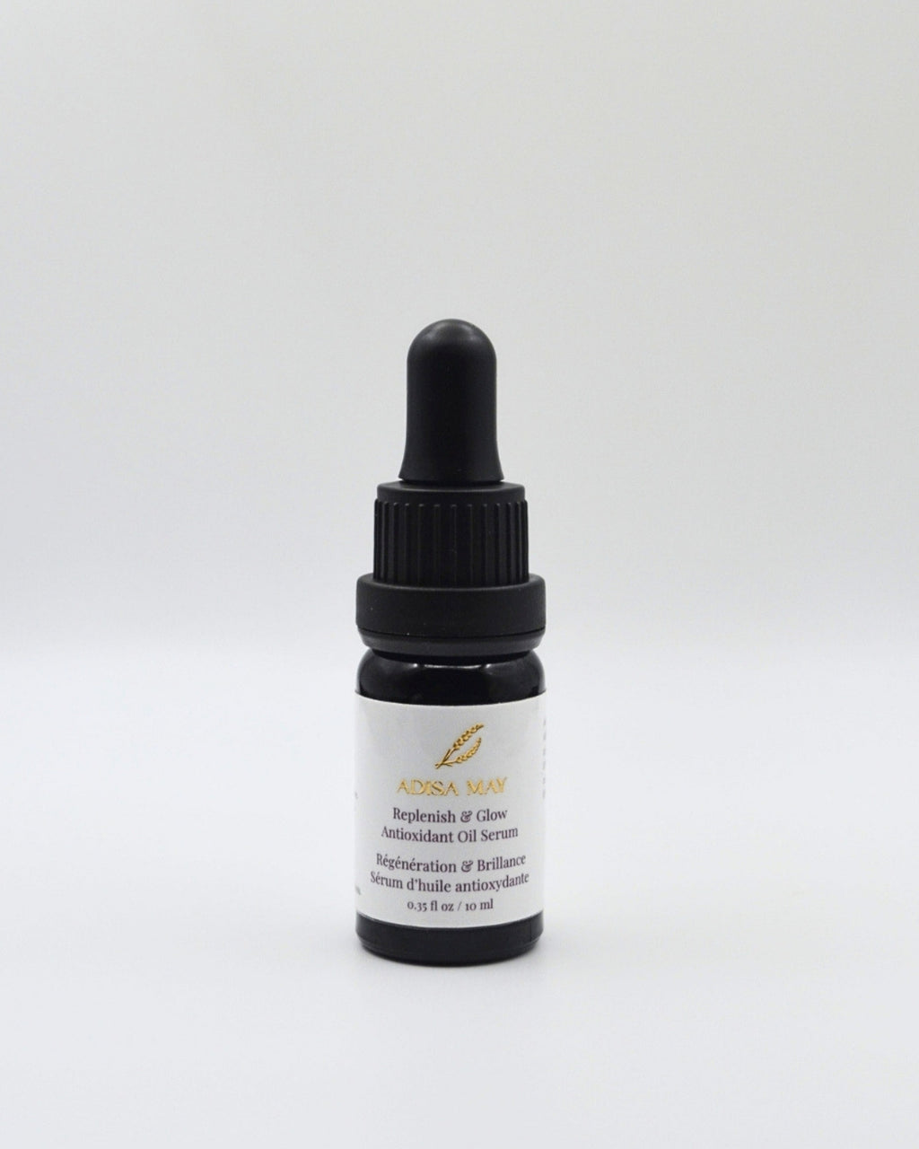 A small dark glass dropper bottle with a black cap and a white label, centered on a light gray background. The label reads 'ADISA MAY' and 'Replenish & Glow Antioxidant Oil Serum'.