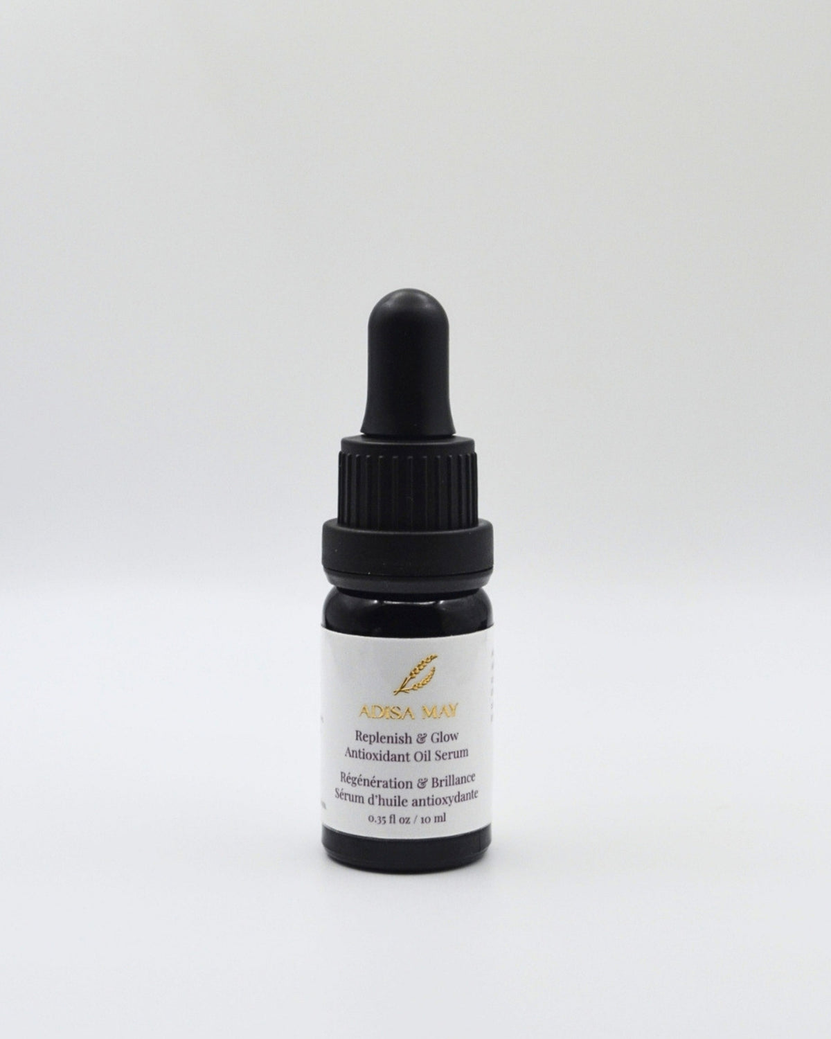 A small dark glass dropper bottle with a black cap and a white label, centered on a light gray background. The label reads 'ADISA MAY' and 'Replenish & Glow Antioxidant Oil Serum'.
