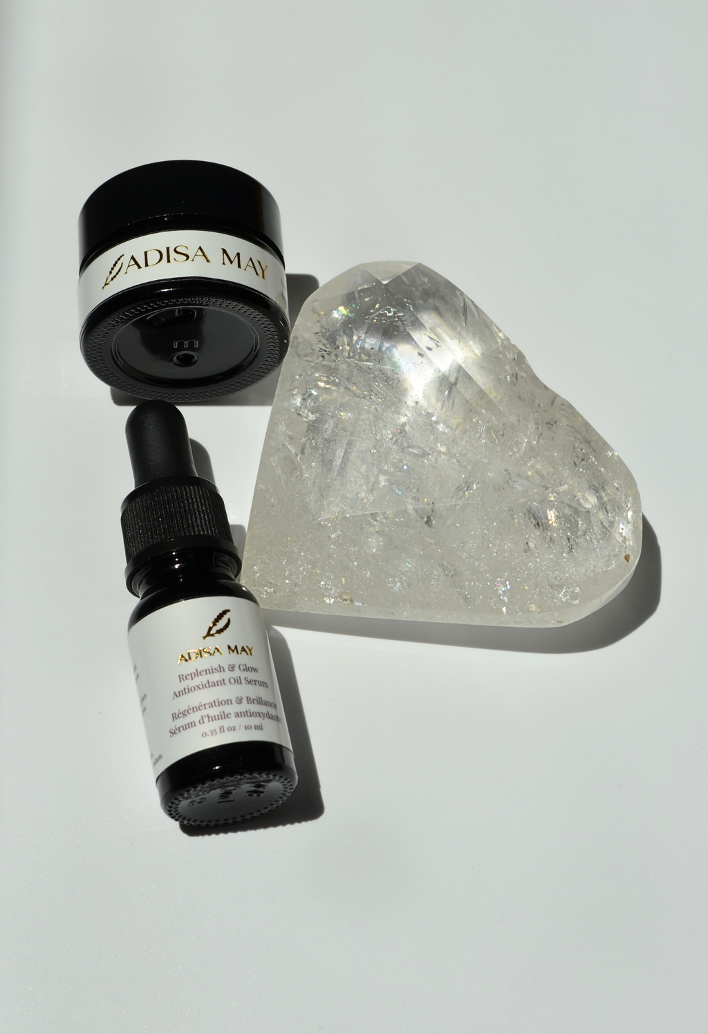 Two black bottles with white labels and a clear crystal heart on a light gray background
