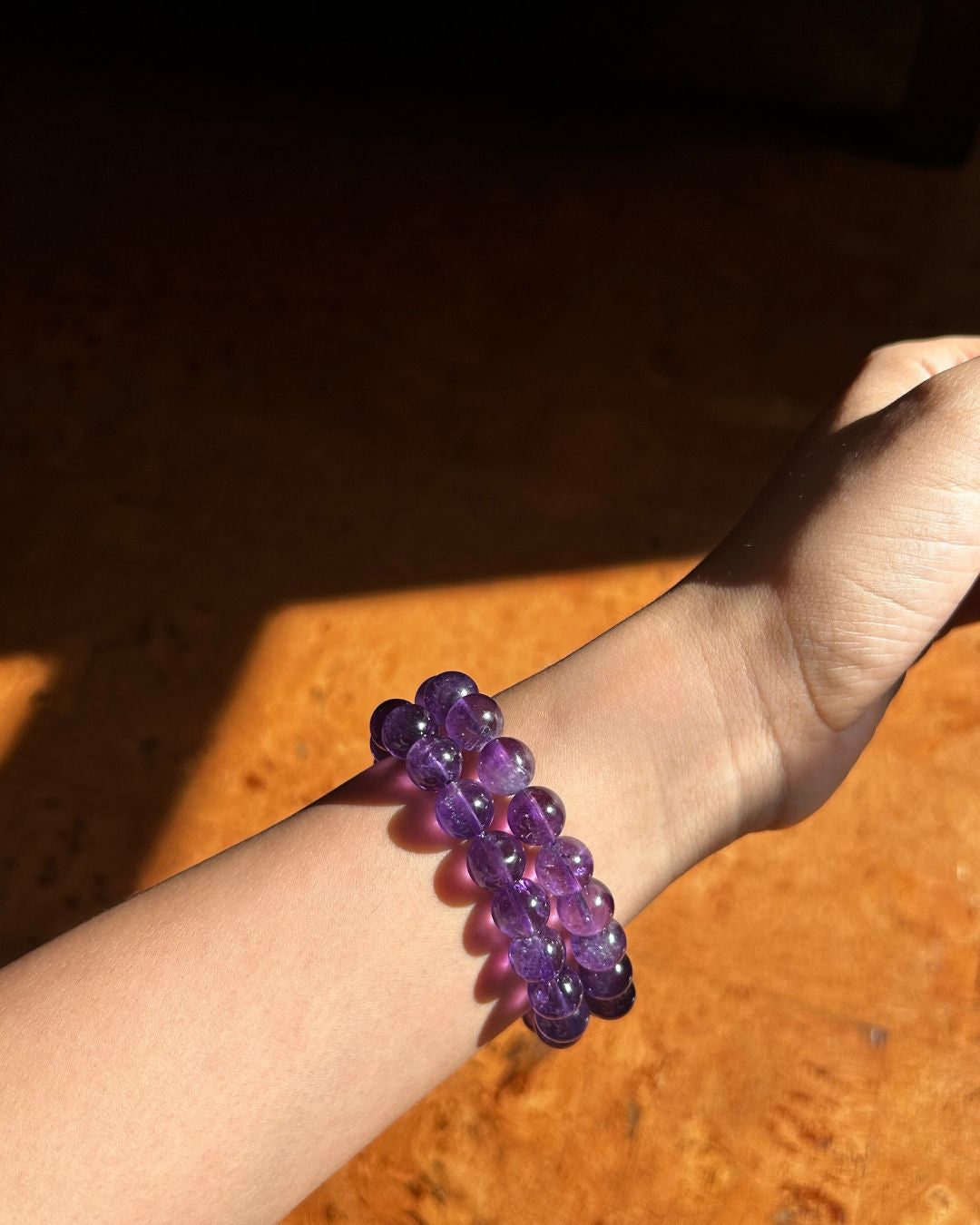 Purple beaded bracelet on a wrist with a wooden surface in the background