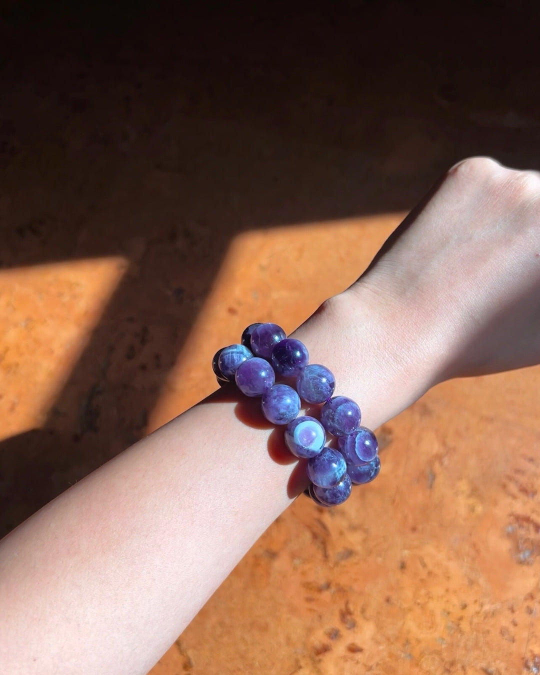 Purple beaded bracelet on a wrist with a wooden surface background