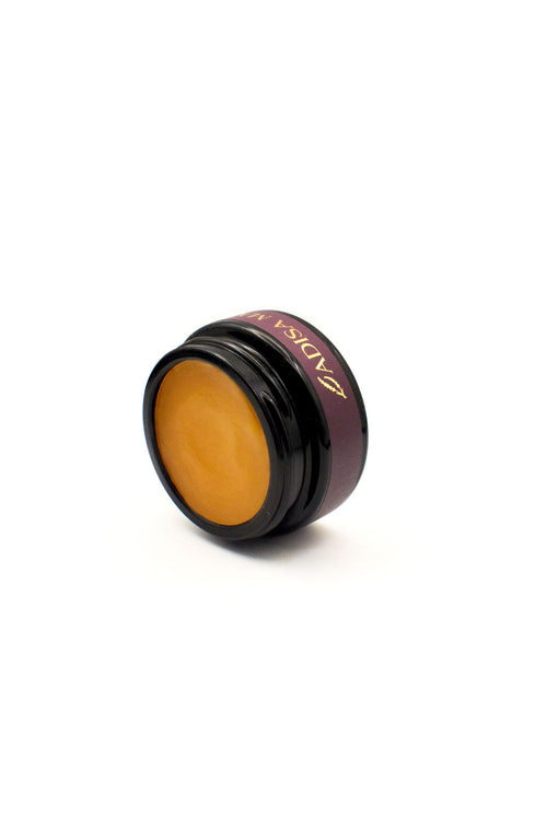 Gold coloured cosmetic product for dry skin with a purple label on the jar on a white background