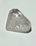 A raw, unpolished clear quartz crystal point with natural inclusions, displayed on a clean white background with a soft shadow.