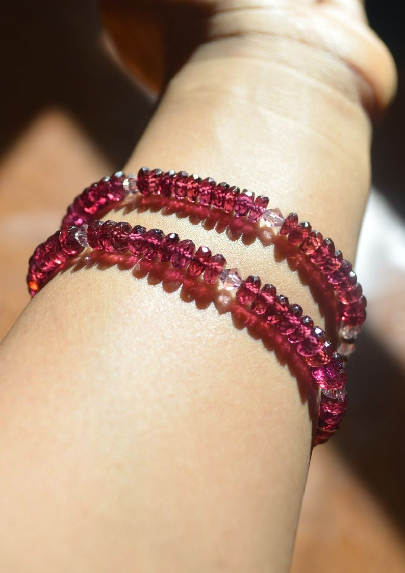 Close-up of a wrist wearing two red beaded bracelets.