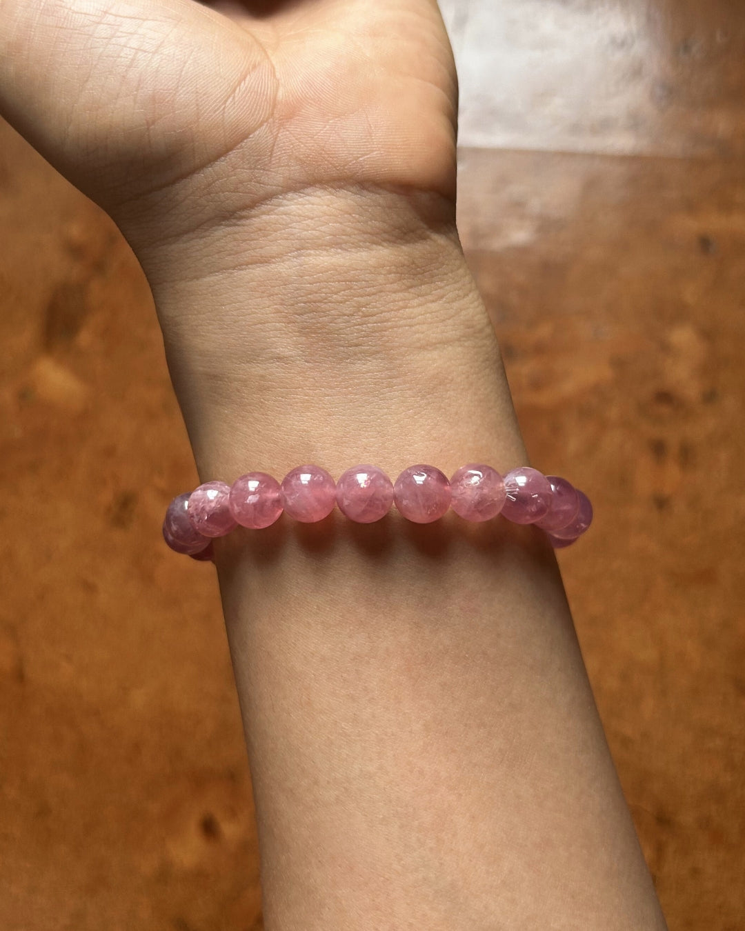 Pink beaded bracelet on a wrist with a wooden background