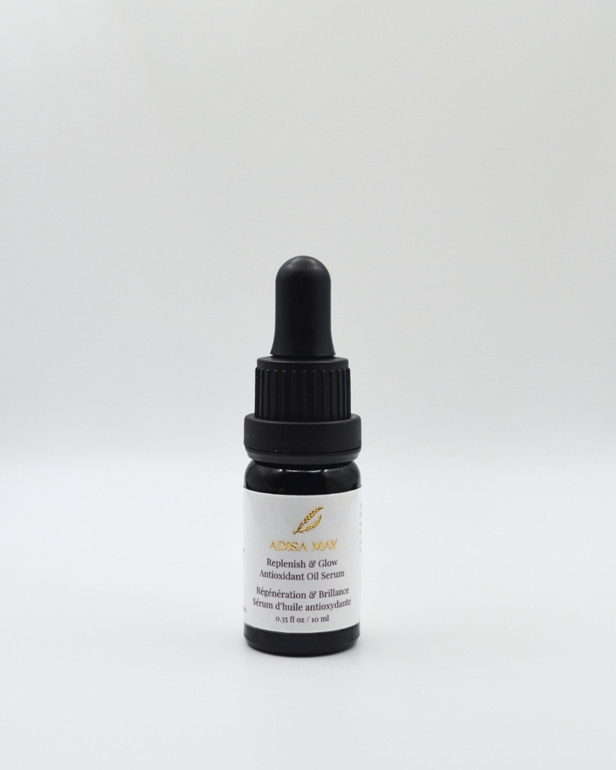 A small dark glass dropper bottle with a black cap and a white label, centered on a light gray background. The label reads 'ADISA MAY' and 'Replenish & Glow Antioxidant Oil Serum'.