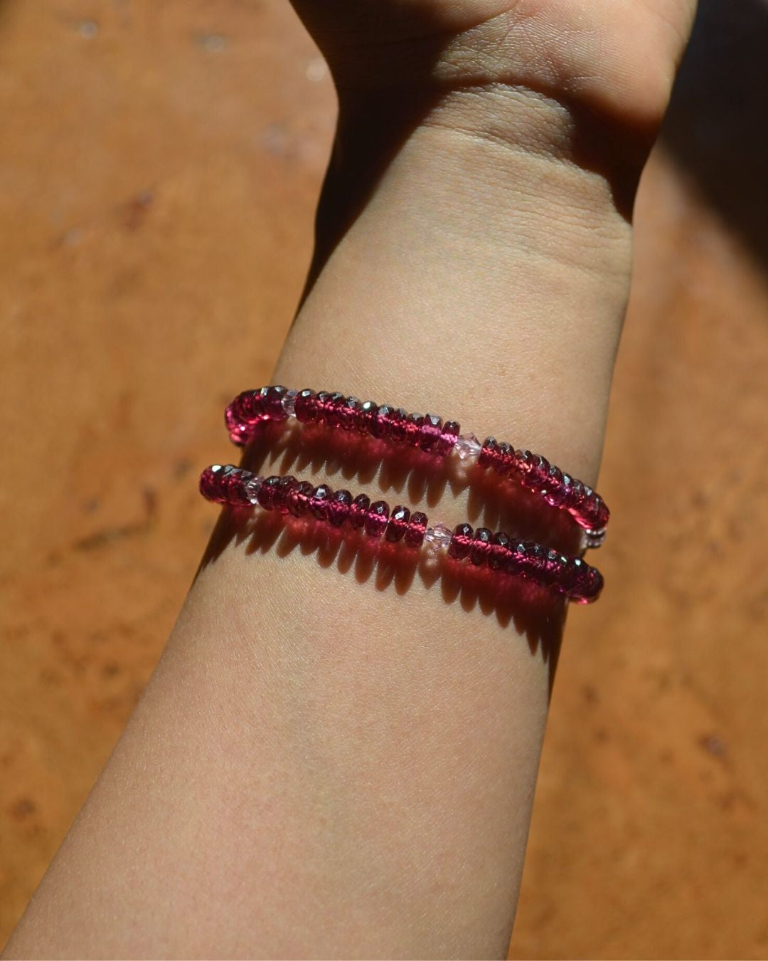 Two beaded bracelets on a wrist against a wooden background