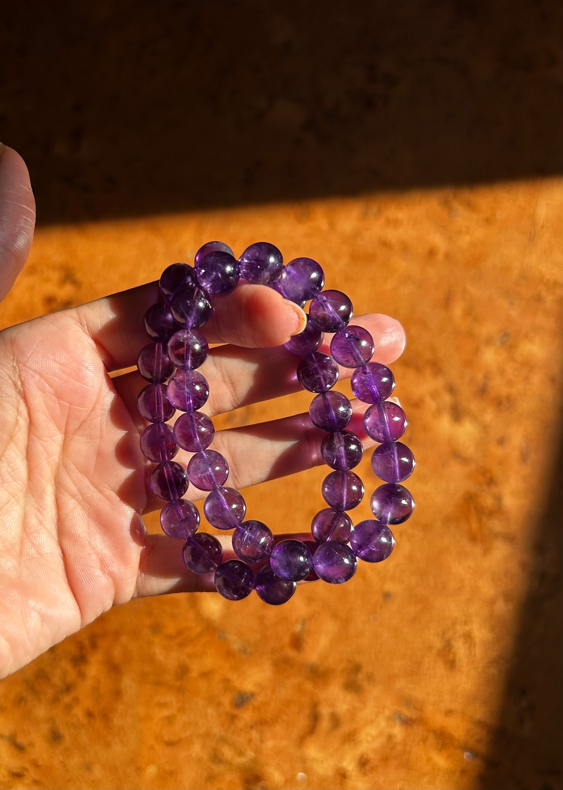 Purple beaded bracelet held in a hand on a wooden surface
