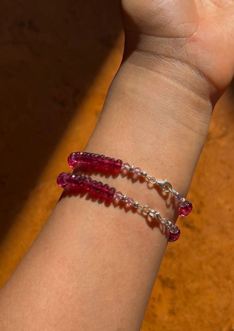 Bracelet with red beads on a wrist against an orange background