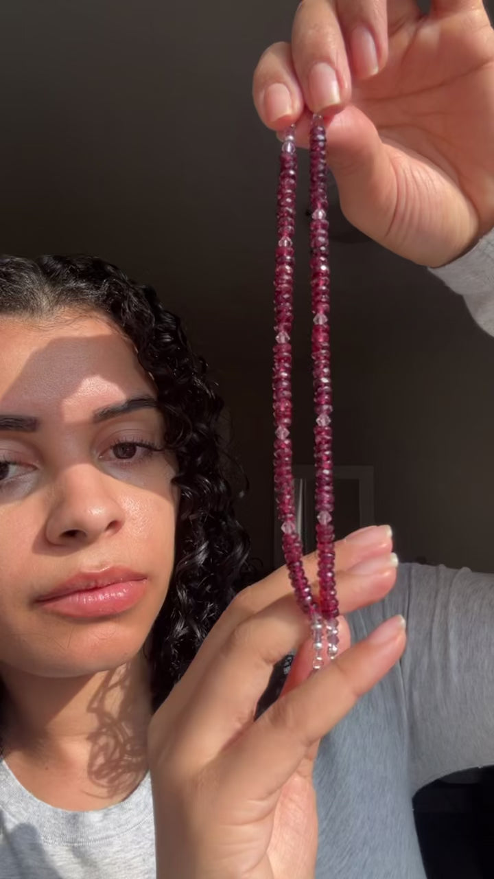 Woman holding two red bracelets shimmering in the light