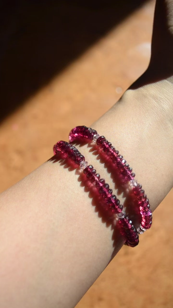 a hand with two gemstone red braceletson